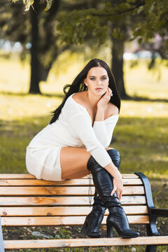 Beautiful Young Woman With Long Hair Sits On A Bench In A City Park