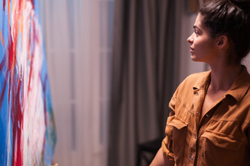 Artist smiling looking at painting in art workshop. Successful painter. Modern artwork paint on...