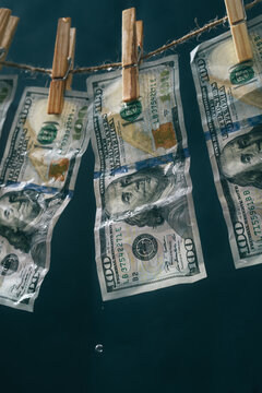 Wet dollars hanging on rope with clothespins