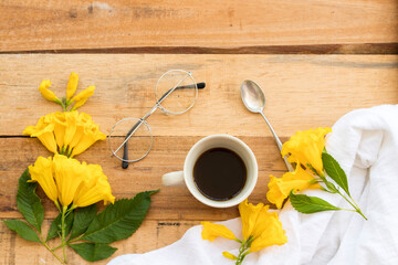 hot coffee espresso with white cloth ,yellow flowers of lifestyle arrangement flat lay style on background wooden