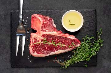 raw t-bone steak with  on stone background