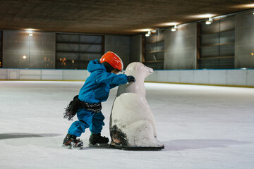 toddler skating on ice rink with the help from a polar bear