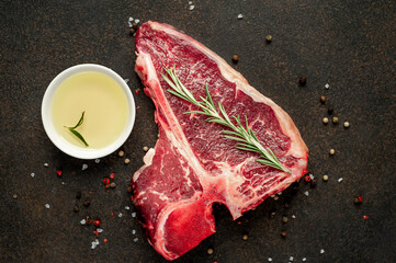 raw t-bone steak with ingredients on stone background 