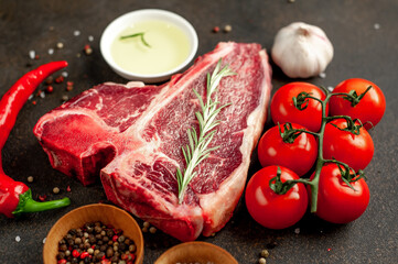 raw t-bone steak with ingredients on stone background 