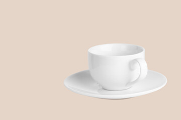 White coffee cup on saucer on a pale pink background.