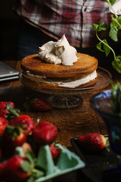 A dollop of cream on the top of a homemade sponge in the process of finishing the cake.