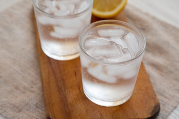 Fresh Lemon Sparkling Water with Ice on a rustic wooden board, low angle view.