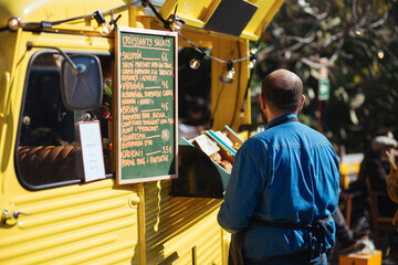 Young man standing before yellow food truck