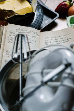 Genoise sponge recipe on handwritten recipe book,partly obscured by kitchen equipment.
