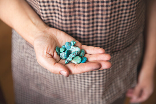 close up of jewellers hand holding turquoise beads