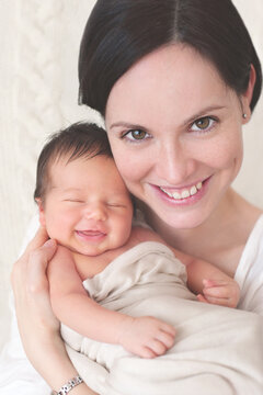 Portrait of a happy mother with her smiling newborn baby in her arms