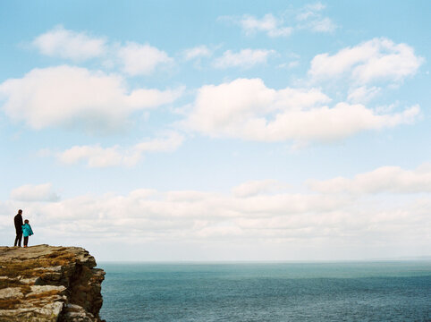 Father and son look out over the sea at Tintagel, Cornwall