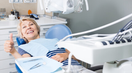 Portrait of smiling satisfied woman visiting dentist giving thumbs up