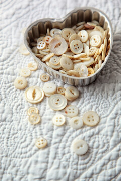 Heart shaped container with pearl buttons on a quilt