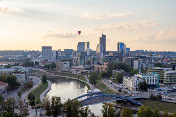 Fototapeta na wymiar anorama of Vilnius at sunset in August 2020. City buildings. Skyscrapers on the horizon. Blue sky over the city. Clouds and sun at sunset. Summer evening. A quiet day at the weekend