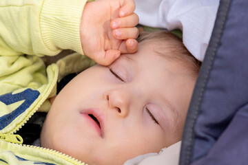 Close-up portrait of a boy with disability lying in pram and sleeping. Cerebral palsy child. Special needs child.