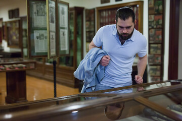 Adult man looking at exhibits in glazed stands in historical museum. High quality photo