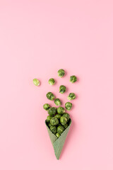 Green ice cream cone with broccoli on pink pastel background. Minimal vegan concept. Fall background. Flat pay.