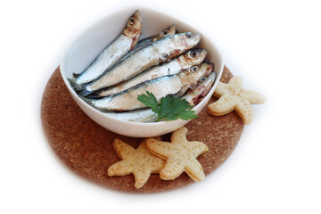 Fresh raw sardines in a bowl with parsley leaves isolated on white. Sardina pilchardus
