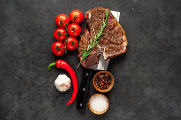 grill t-bone steak with ingredients on a meat knife on stone background