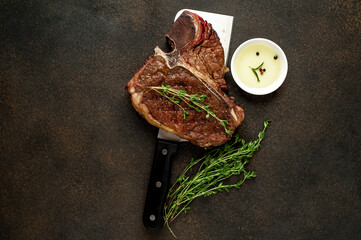 grill t-bone steak with ingredients on a meat knife on stone background