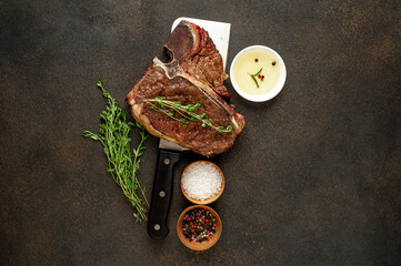 grill t-bone steak with ingredients on a meat knife on stone background