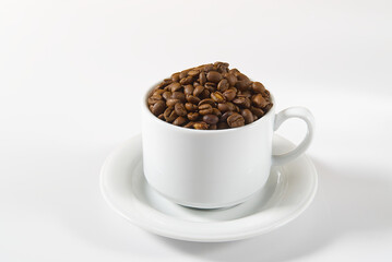Coffee beans in white cup, close-up. White coffee cup with coffee seeds on white background. Concept For International day of coffee.