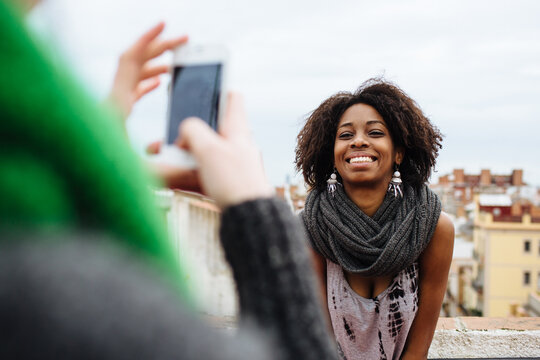 Young woman taking a photo with the phone to her friend