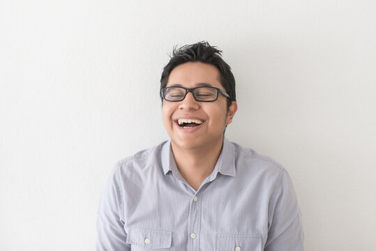 Dark Haired Man With Glasses Laughs On White Wall