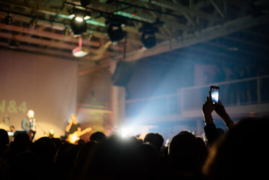 Person photographing a concert from the crowd with mobile phone