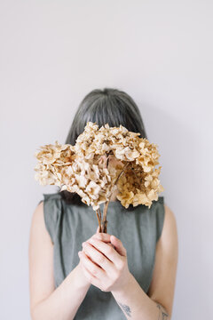 Woman hiding behing bouquet of flowers.