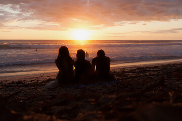 Three friends watching the sunset on the beach.