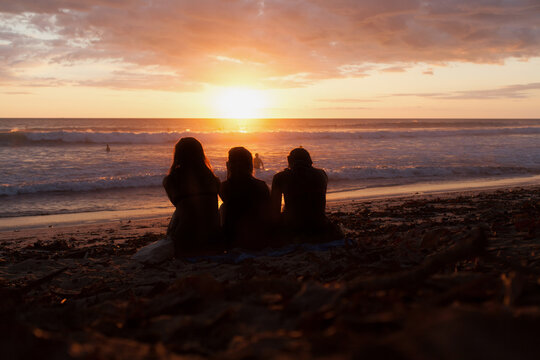 Three friends watching the sunset on the beach.