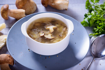 Mushroom soup plate with porcini mushrooms, fresh parsley and pepper on rustic texture background