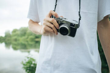 Guy holding retro looking camera in front of lake