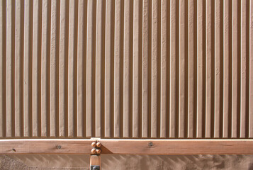 Surface of the wall with a decorative light beige plaster. Textured concrete wall with vertical lines and stripes as a texture or background.