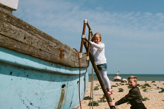 Two children climbing a ladder on to a derelict boat