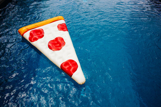 A pizza float floating in a blue pool.