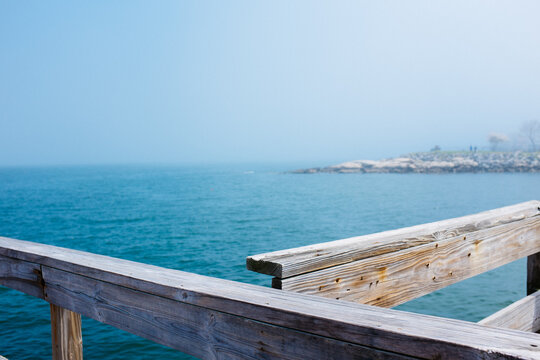 A foggy view of the blue ocean from a cross section of a pier.