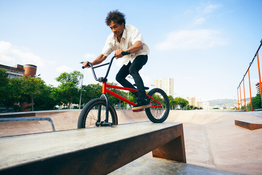 Young man doing acrobatic tricks with his BMX bike in a skate park.