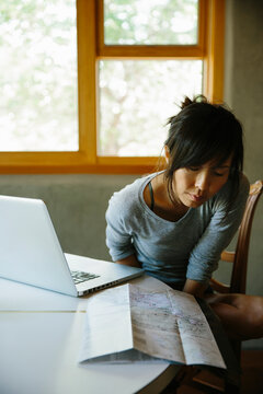 Woman planning a road trip with map and laptop
