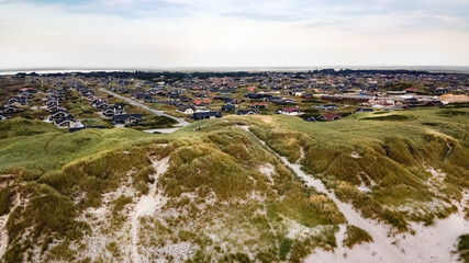 Fototapeta na wymiar Luftaufnahme des Sonnenuntergangs an der Nordsee, Blick auf Dünen und Feriendorf in Dänemark