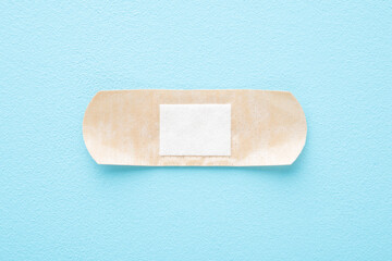 New adhesive bandage on light blue table background. Pastel color. Medical concept. Close up. Top down view.