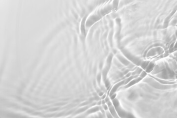 Blurred desaturated transparent clear calm water surface texture with splashes and bubbles. Trendy abstract nature background. White-grey water waves in sunlight. Copy space.