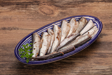 Anchovies in the bowl served basil leaves