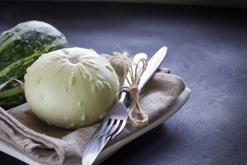 Pumpkins on black background, Halloween or Thanksgiving place settings, fork and knife, napkin, white and green pumpkins on black background