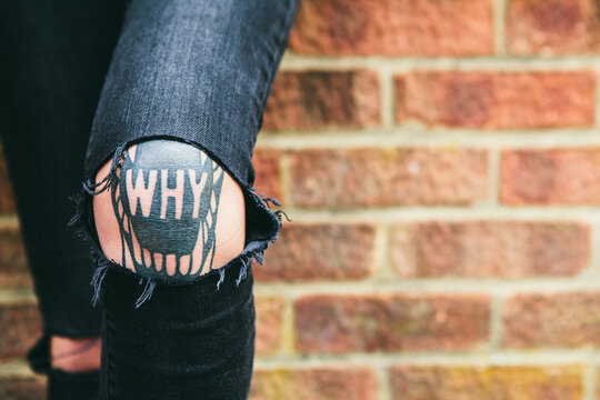 Womans tattoo on her knee spelling 'why'