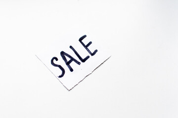 a white sign with the inscription sale lies on a white background. white sign