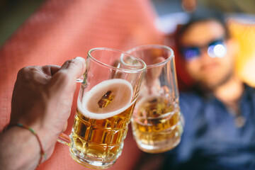Young man hand holding a beer and cheering with a friend