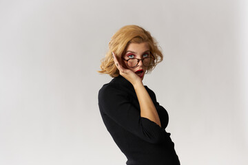 Fototapeta premium Blonde girl with glasses red lips black blouse cropped view glamor light background studio